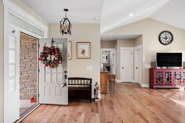 entryway featuring wood finished floors, an inviting chandelier, baseboards, and vaulted ceiling