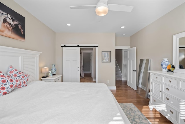 bedroom with baseboards, recessed lighting, a barn door, ceiling fan, and wood finished floors