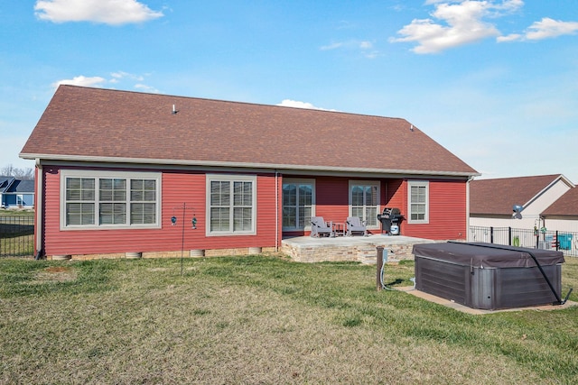 back of property with a patio, a hot tub, a yard, fence, and a shingled roof