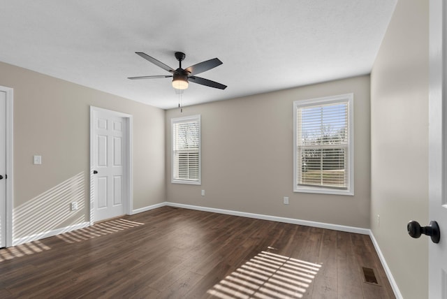 530 S Oak St, Hohenwald, TN 38462 - unfurnished bedroom featuring dark wood-type flooring, visible vents, baseboards, and multiple windows