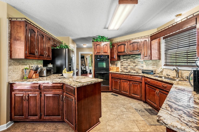 1712 Lake Grassland W, Gallatin, TN 37066 - kitchen featuring black appliances, a sink, light stone counters, a peninsula, and decorative backsplash
