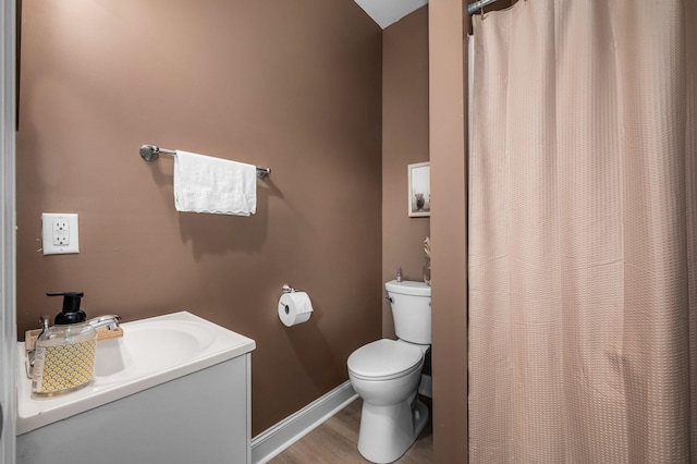 bathroom featuring a shower with curtain, toilet, wood finished floors, baseboards, and vanity