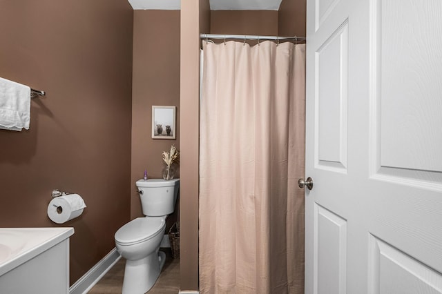 bathroom featuring curtained shower, baseboards, toilet, and vanity