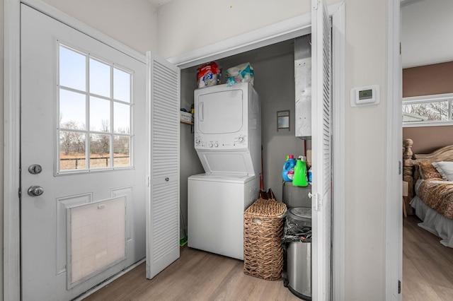 washroom featuring light wood-type flooring, stacked washer / drying machine, and laundry area