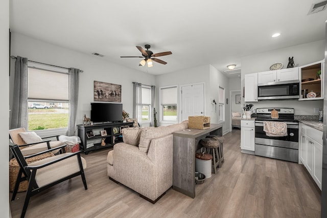 living area with visible vents, light wood-type flooring, and ceiling fan