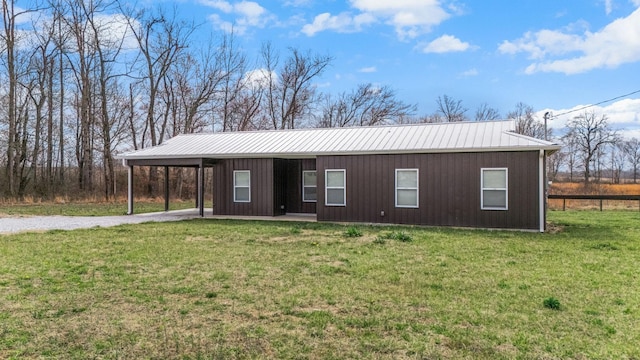 view of front facade with metal roof, a carport, gravel driveway, and a front yard