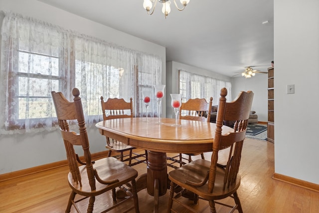 dining area with ceiling fan with notable chandelier, light wood-style floors, and baseboards