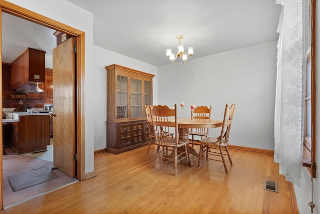 dining space with visible vents, baseboards, a notable chandelier, and light wood-style flooring