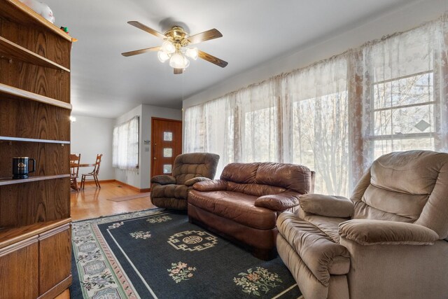 living area featuring baseboards, wood finished floors, and ceiling fan