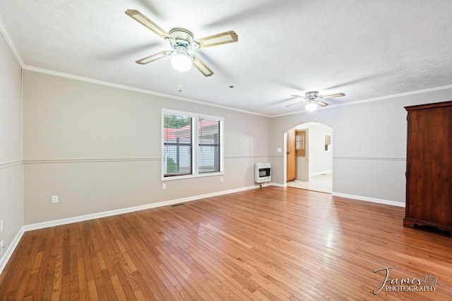 empty room with heating unit, light wood-style floors, arched walkways, and ceiling fan