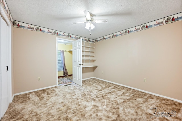 unfurnished bedroom featuring ceiling fan, a textured ceiling, baseboards, and carpet floors