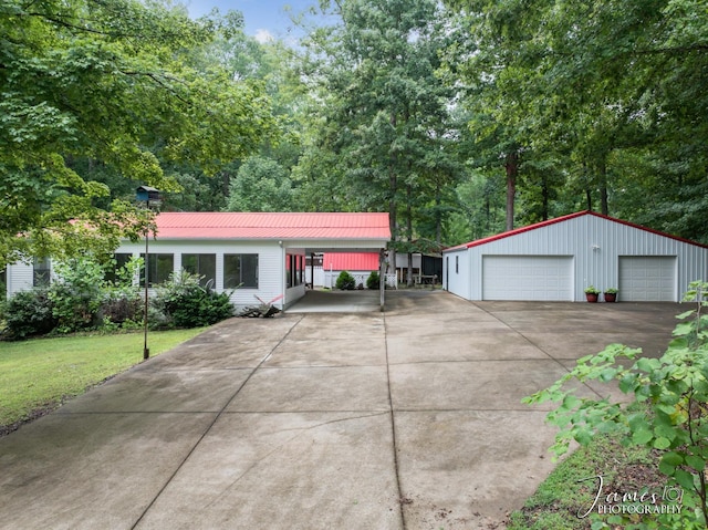 view of front of property with an outbuilding, a garage, a front yard, and metal roof
