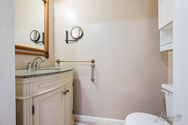 half bathroom with toilet, vanity, and baseboards