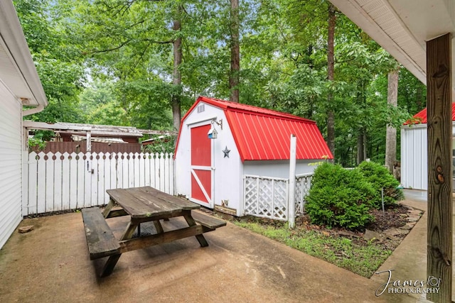 view of patio with an outdoor structure, outdoor dining area, fence, and a shed