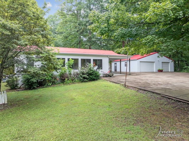 view of front facade with a garage, metal roof, a front yard, and an outdoor structure
