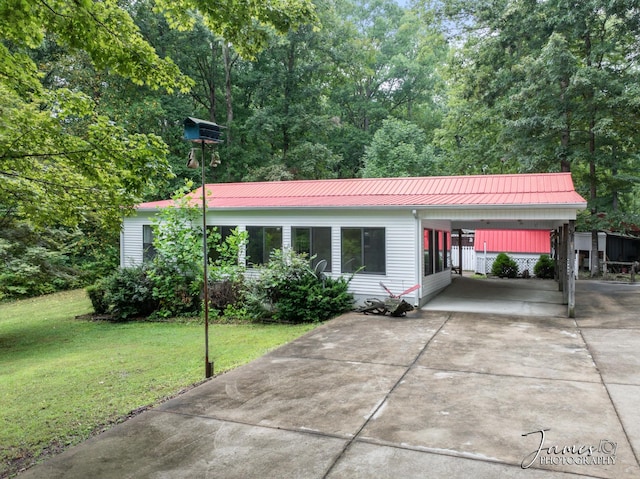 view of front of house with an attached carport, concrete driveway, a front lawn, and metal roof