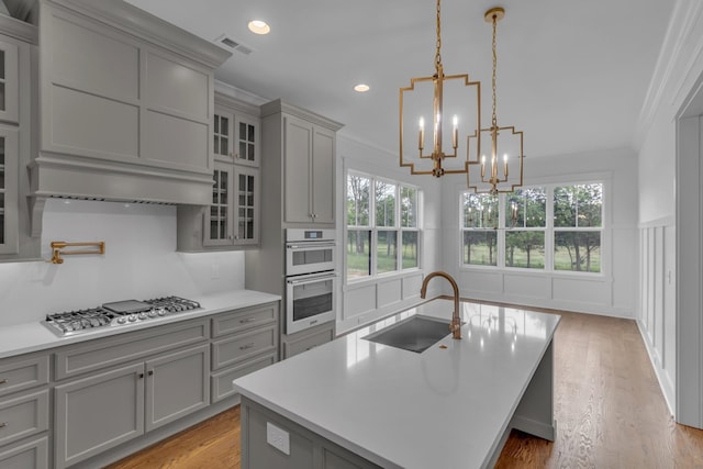 7004 Twelve Corners Rd, Lascassas, TN 37085 - kitchen with a sink, gray cabinets, stainless steel gas cooktop, crown molding, and a chandelier