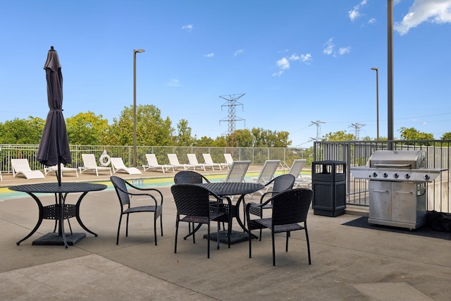 view of patio / terrace featuring a community pool, a grill, and fence