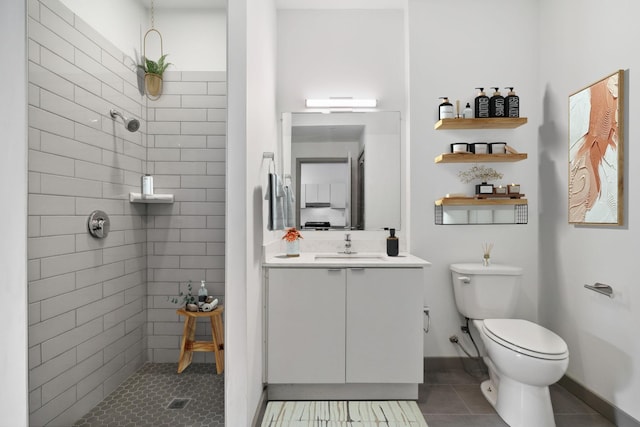 bathroom with tile patterned flooring, a tile shower, toilet, and vanity