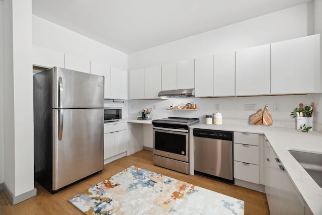 kitchen featuring a sink, light wood-type flooring, white cabinetry, under cabinet range hood, and appliances with stainless steel finishes