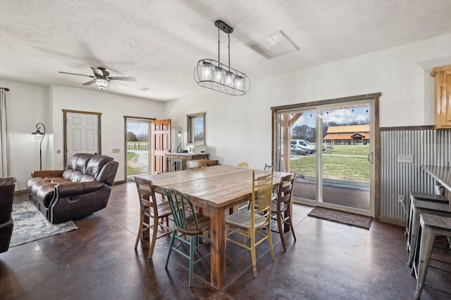 dining room with plenty of natural light, a textured ceiling, concrete flooring, and ceiling fan