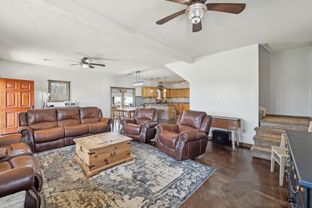 living room featuring stairway, a ceiling fan, baseboards, beam ceiling, and concrete flooring