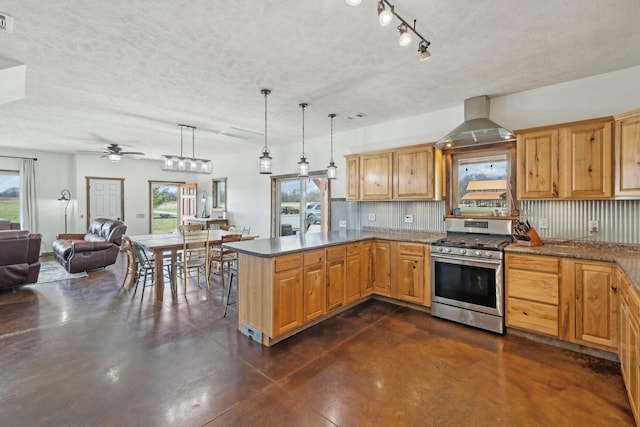 kitchen featuring wall chimney range hood, gas range, concrete flooring, a peninsula, and a ceiling fan