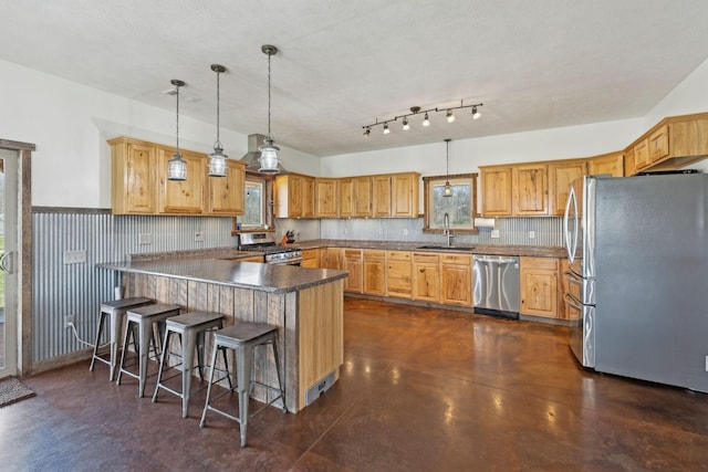 kitchen with a sink, decorative light fixtures, finished concrete floors, appliances with stainless steel finishes, and a peninsula