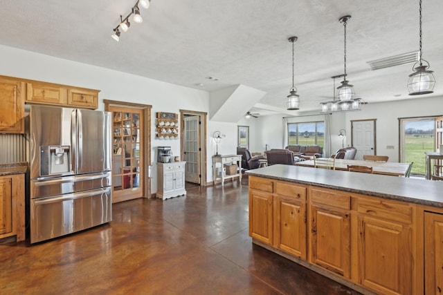 kitchen with visible vents, stainless steel fridge, dark countertops, and concrete flooring