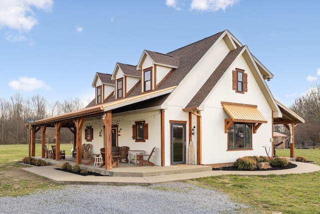 rear view of house featuring a lawn, a patio, and roof with shingles
