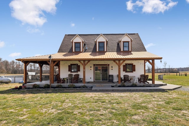 view of front facade with metal roof, fence, a front yard, and stucco siding
