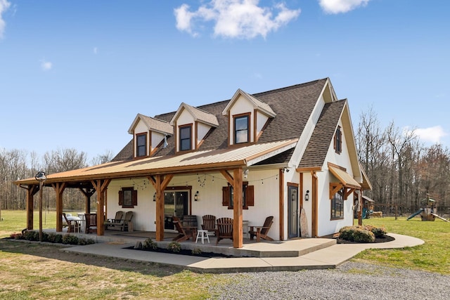 view of front of property featuring a patio, a shingled roof, and a front yard