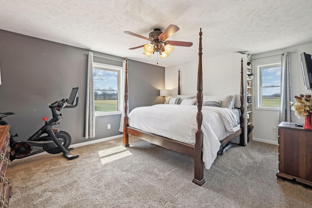 bedroom with baseboards, a textured ceiling, carpet floors, and a ceiling fan