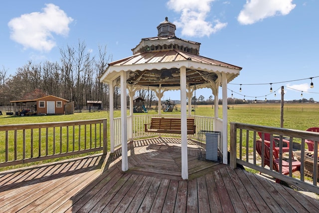 wooden terrace with a gazebo, a rural view, a lawn, and an outdoor structure