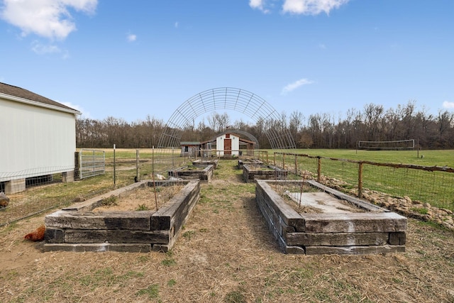 view of yard with a rural view, an outdoor structure, a garden, and fence
