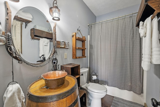 bathroom with shower / tub combo with curtain, a textured ceiling, toilet, and vanity