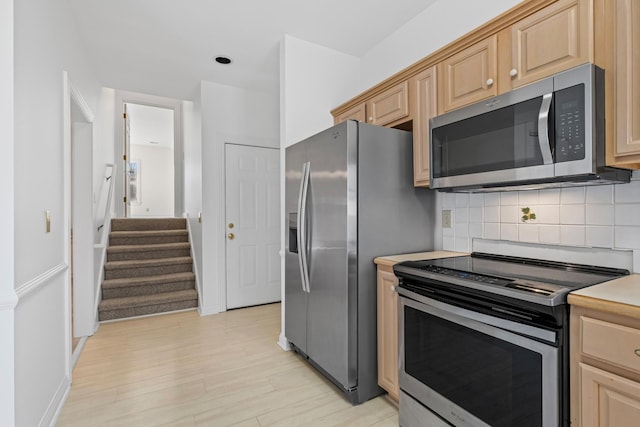kitchen featuring light wood-style flooring, light brown cabinetry, stainless steel appliances, light countertops, and decorative backsplash