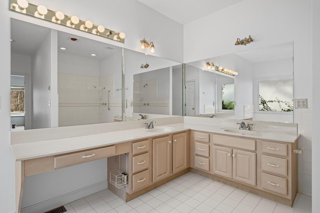 bathroom with double vanity, tile patterned flooring, a tile shower, and a sink