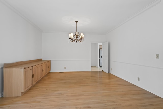 unfurnished room with ornamental molding, light wood-type flooring, and a chandelier