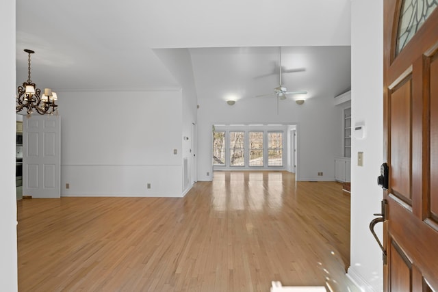 foyer entrance featuring baseboards, light wood-style floors, a towering ceiling, and ceiling fan with notable chandelier