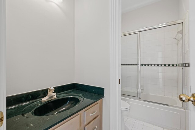 full bathroom featuring tile patterned floors, bath / shower combo with glass door, toilet, and vanity