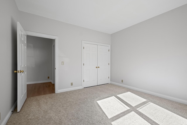 unfurnished bedroom with baseboards, a closet, and light carpet