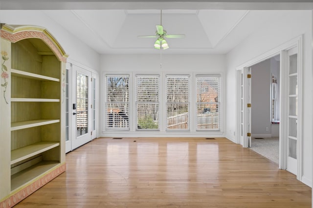 unfurnished sunroom with a raised ceiling and ceiling fan