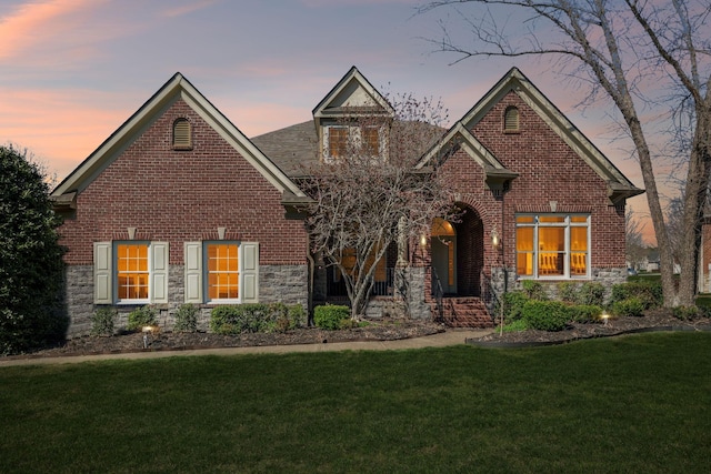 view of front of home featuring stone siding, brick siding, and a front lawn