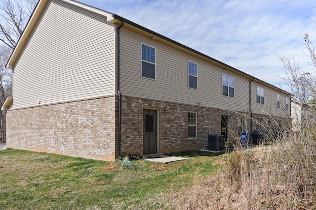 back of house featuring a yard, brick siding, and central AC
