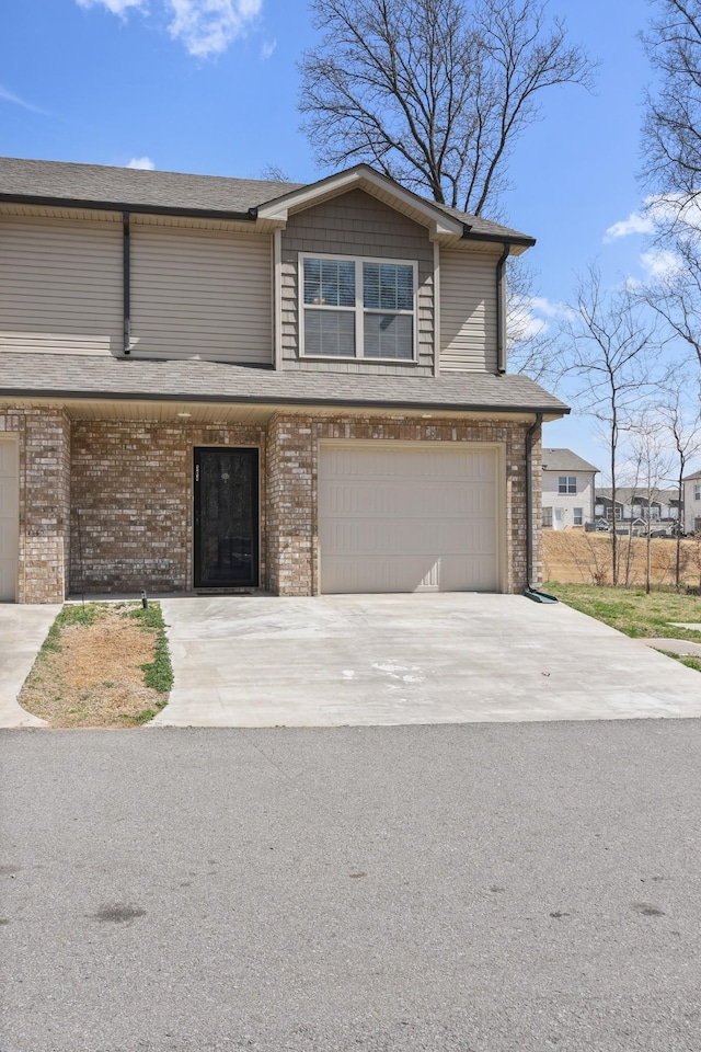 view of front facade featuring driveway, brick siding, and an attached garage