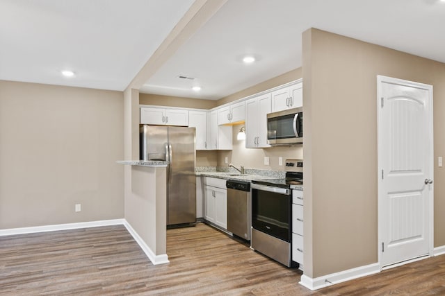 kitchen featuring stainless steel appliances, white cabinetry, baseboards, and light wood finished floors