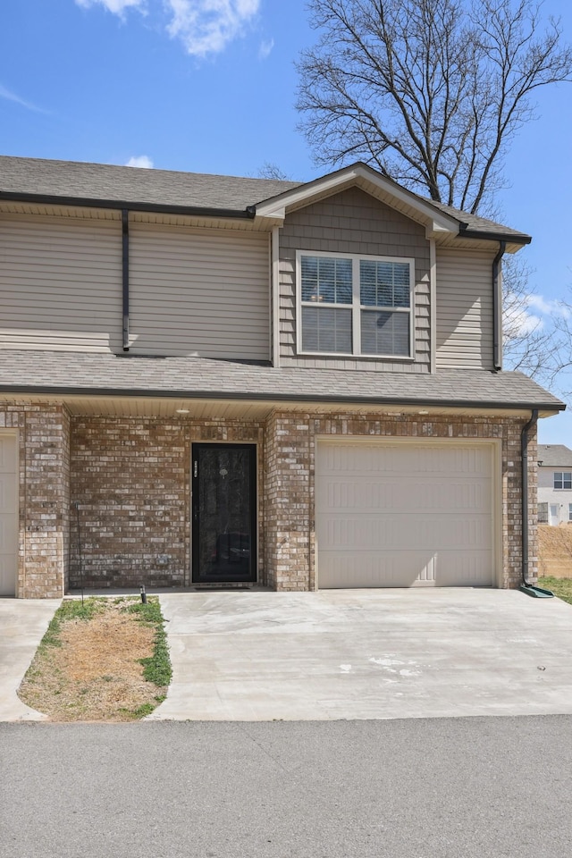 townhome / multi-family property with brick siding, driveway, and a garage