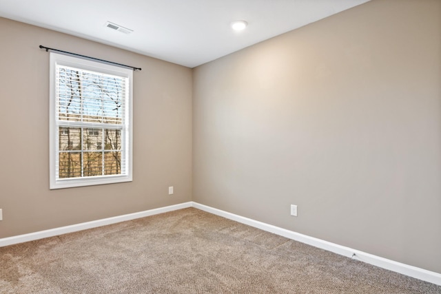 carpeted spare room featuring visible vents and baseboards