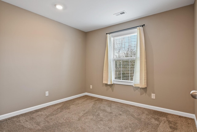 carpeted spare room featuring visible vents and baseboards